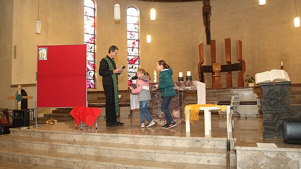 Pfarrer Sturm mit Mikro im Gespräch mit zwei Kindern