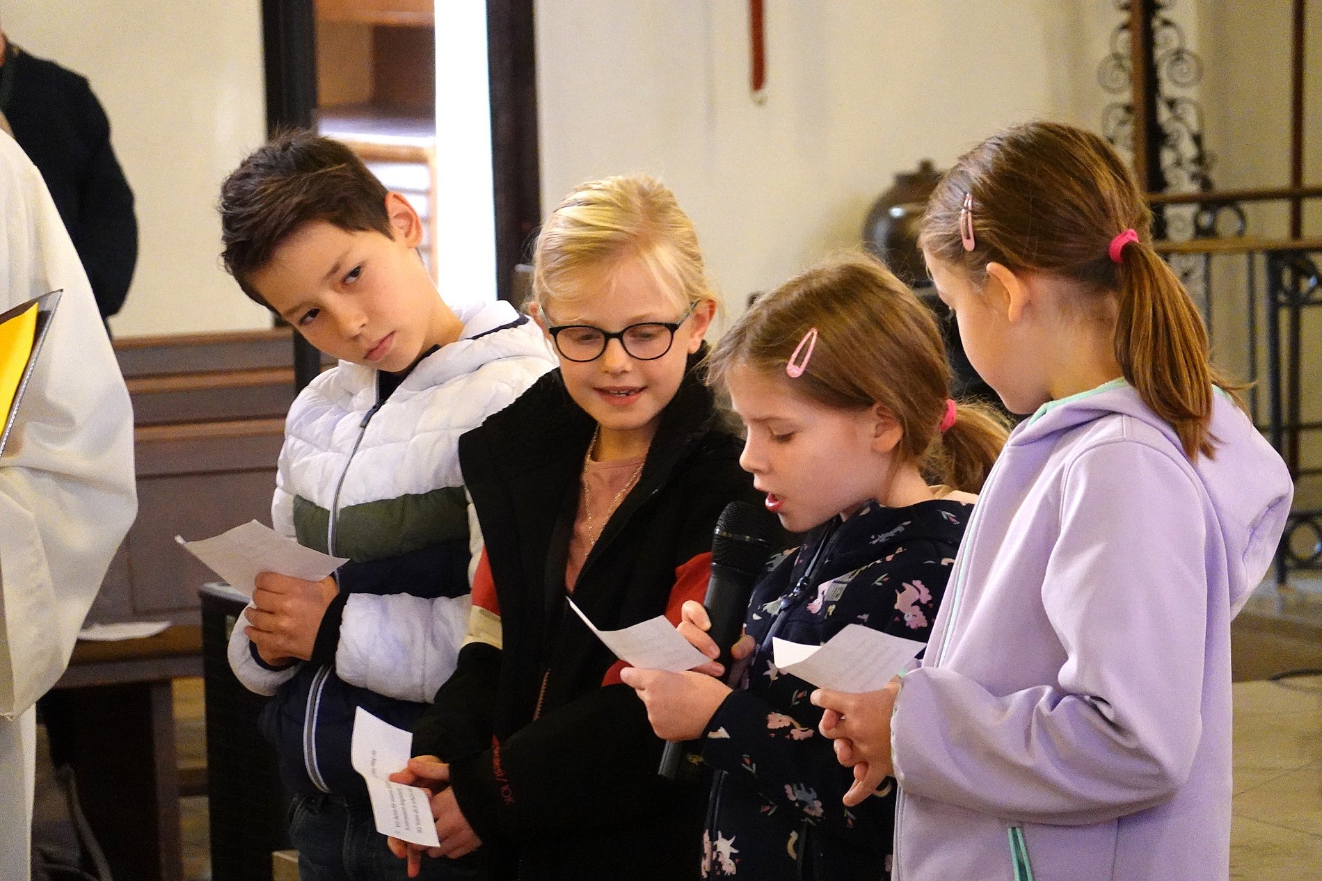 Vier Kommunionkinder stehen nebeneinander, um Fürbitten vorzulesen