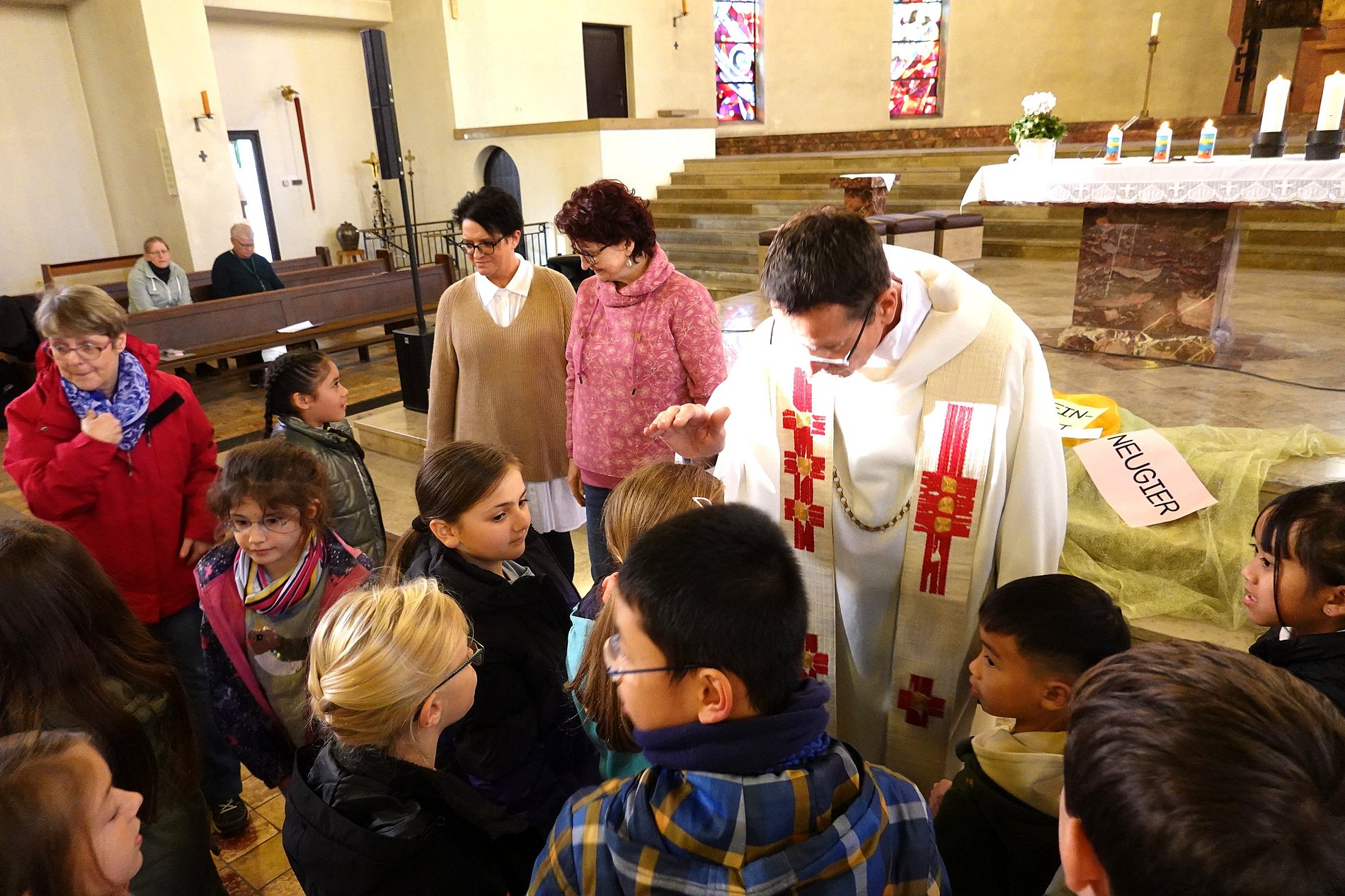 Der Pfarrer hält segnend die Hände über den Kopf der Kommunionkinder