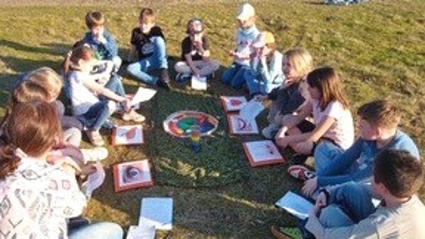 Die Spuren Gottes gefunden? Im Kreis sitzend die Kommunionkinder mit gemalten Bildern