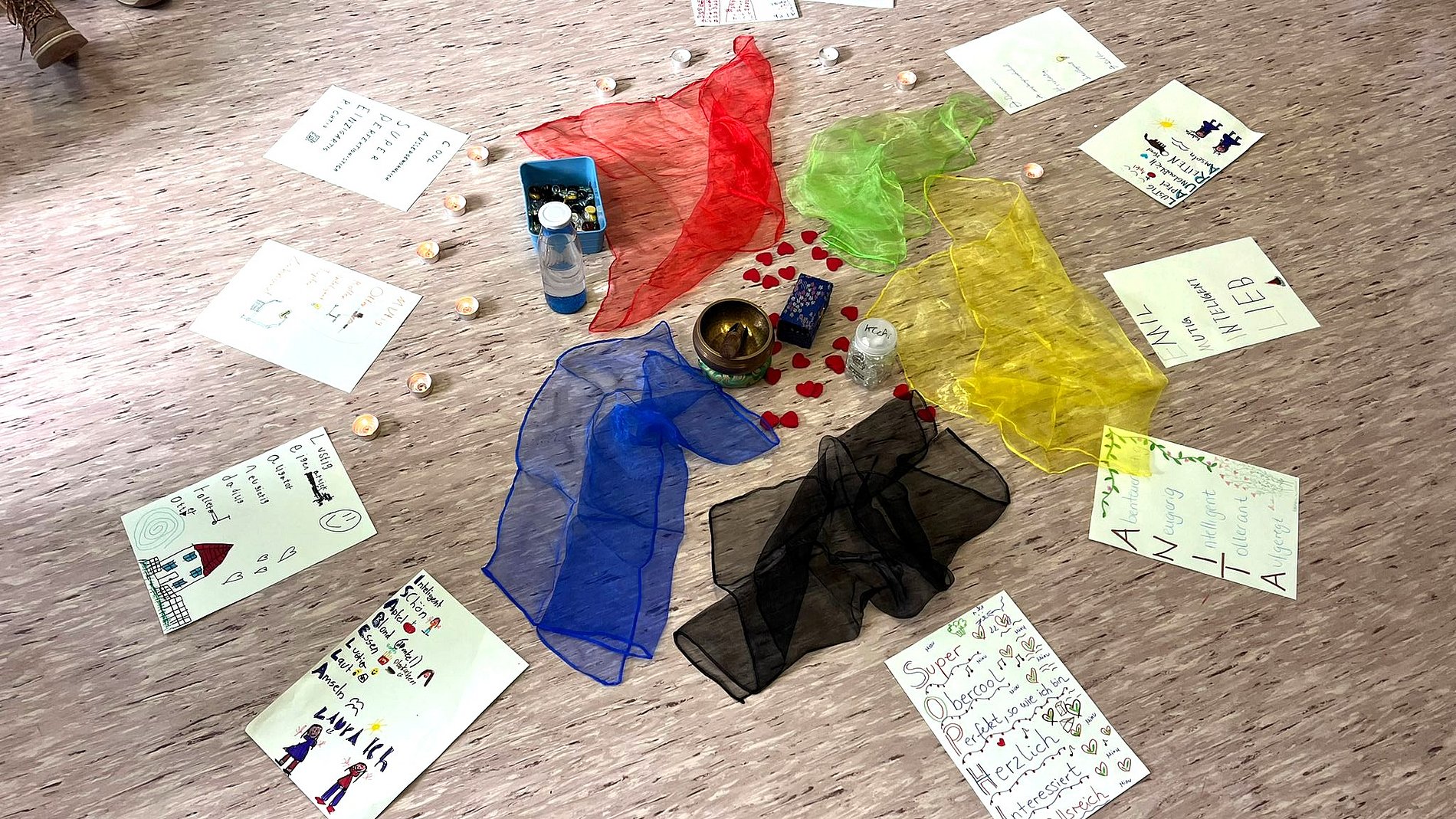 Die Papier mit den Namensbuchstaben-Eigenschaften liegen im Kreis um farbige Tücher.