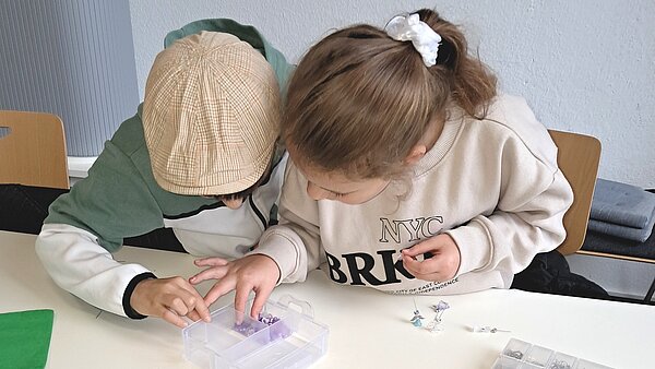 Ein Junge und ein Mädchen suchen nach Perlen zum Auffädeln