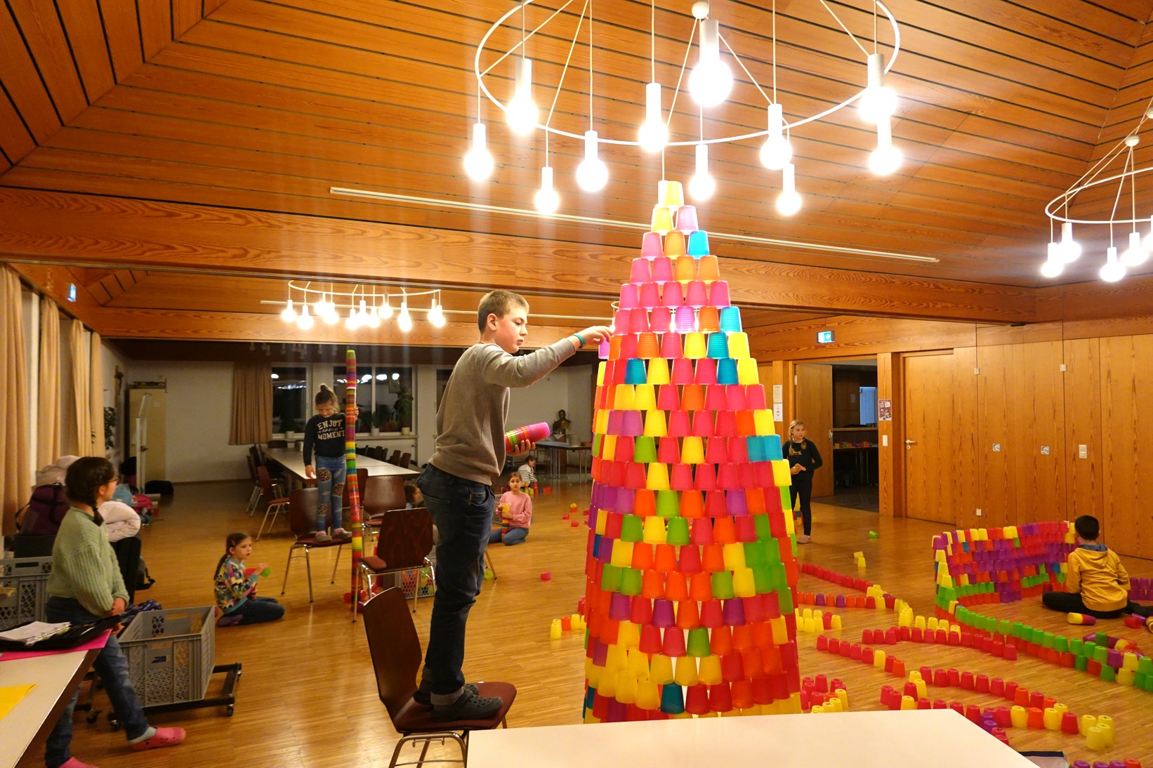 Kommunionkinder stapeln bunte Becher zu Türmen