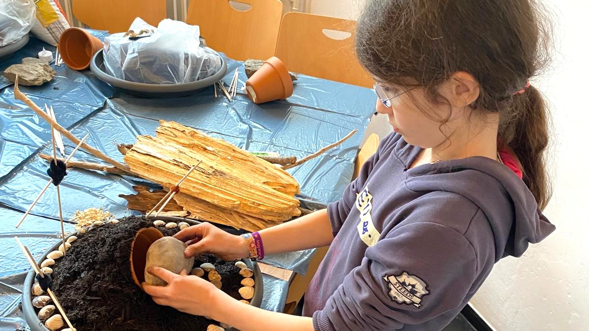 Der Tontopf wird mit Erde bedeckt und bildet eine Höhle